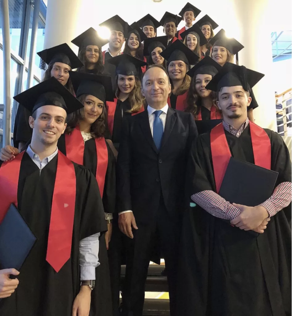 صورة لخريجين عرب ومن دول اخرى يرتدون زي التخرج ويبتسمون في مبنى جامعة في سنغافورة