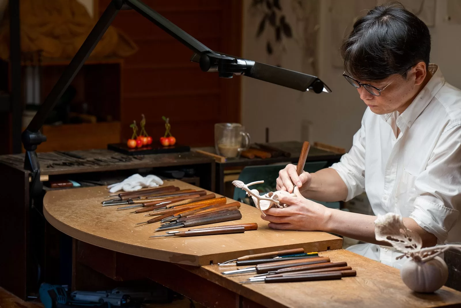 Image may contain Inoran Person Accessories Glasses Cup Woodworking Desk Furniture Table and Pen