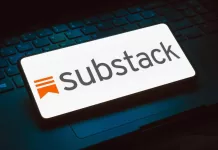 The Substack logo displayed on a phone that is resting on top of a keyboard