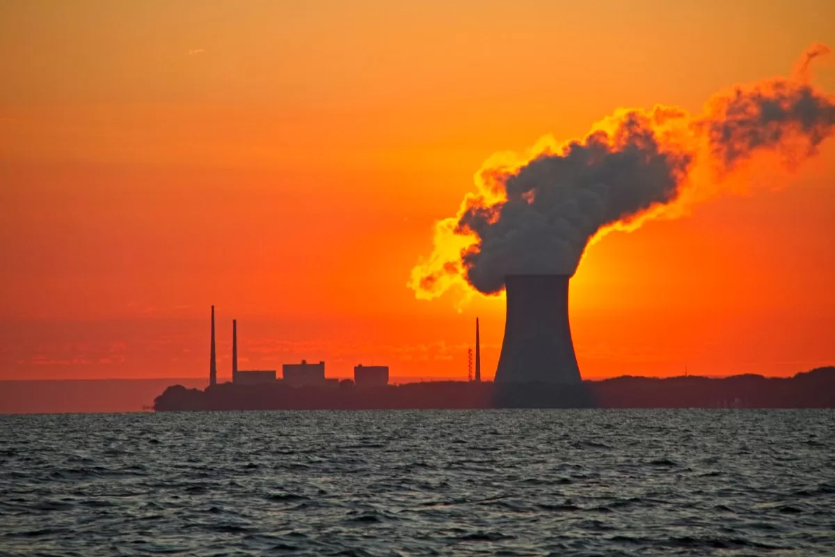 The sun rises behind a nuclear power plant cooling tower.