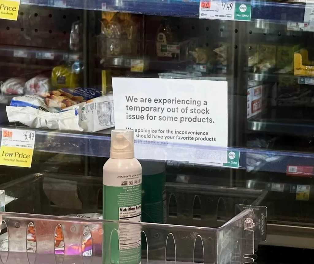 a photo of the frozen and refrigerated section at a local Whole Foods, with empty spaces, and signs warning of an out-of-stock issue.