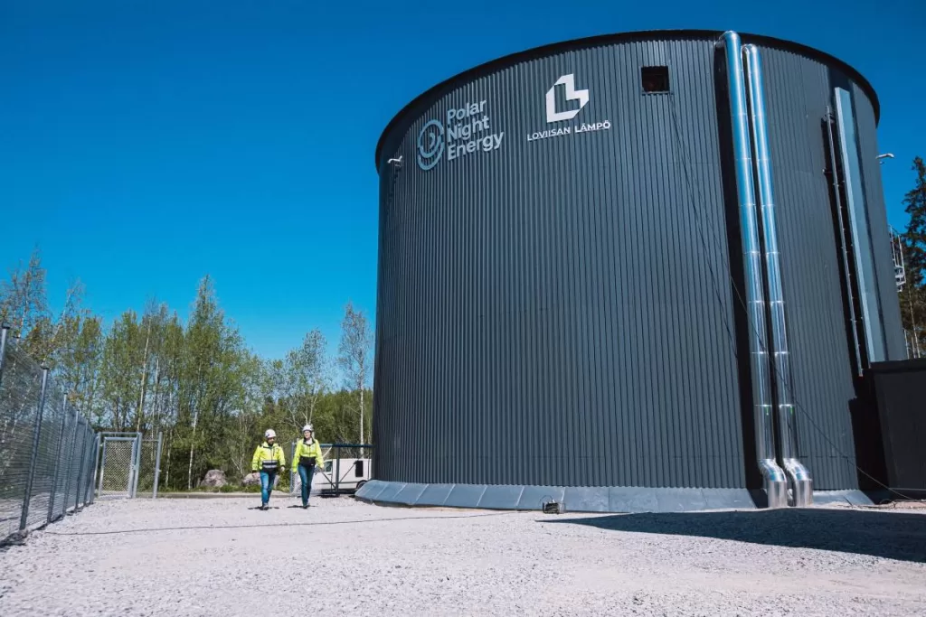 Two technicians walk by the Pornainen sand battery.