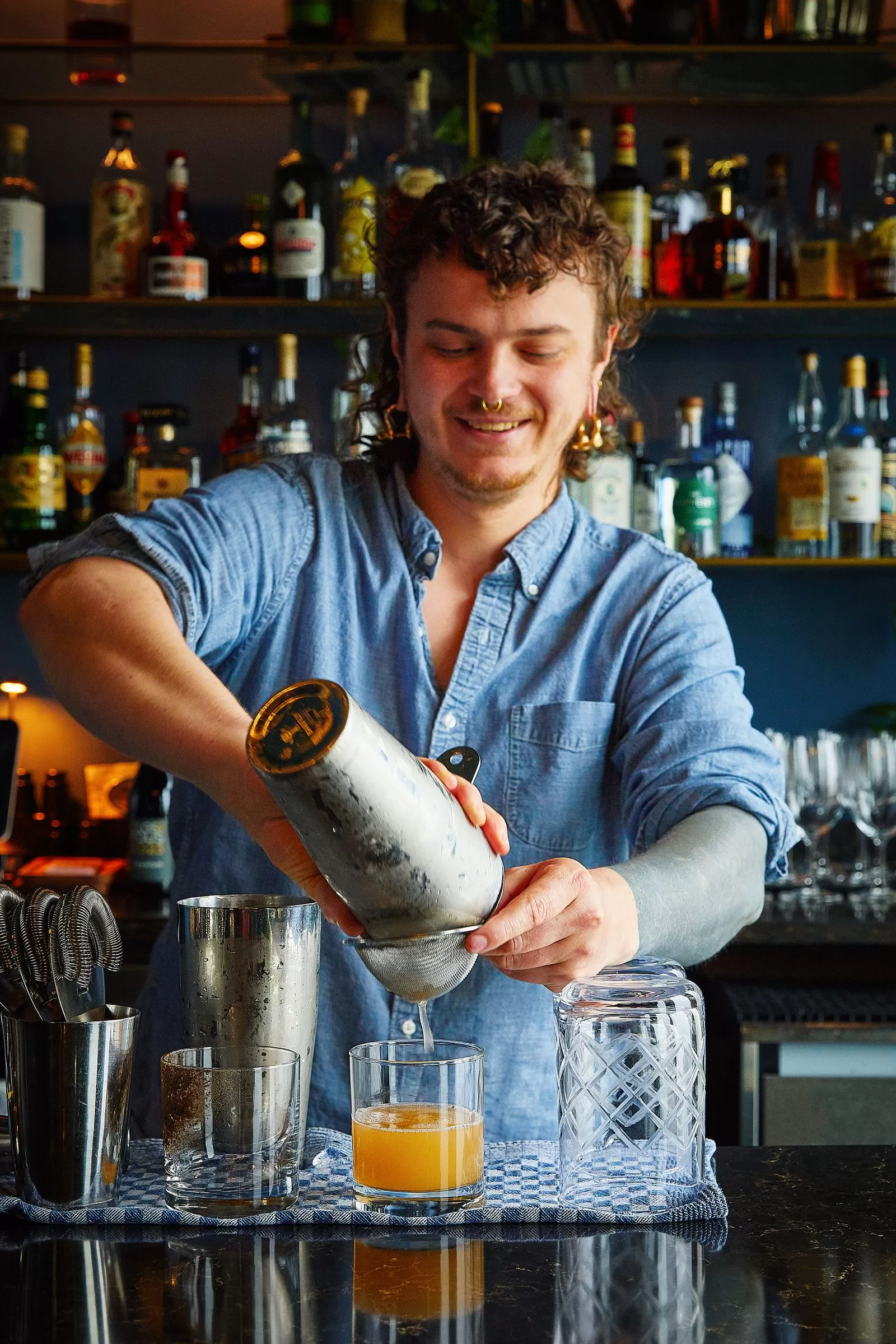 قد تحتوي الصورة على شخص بالغ، كوب، مشروب كحولي، نادل، مشروب، مكتب، أثاث وطاولة