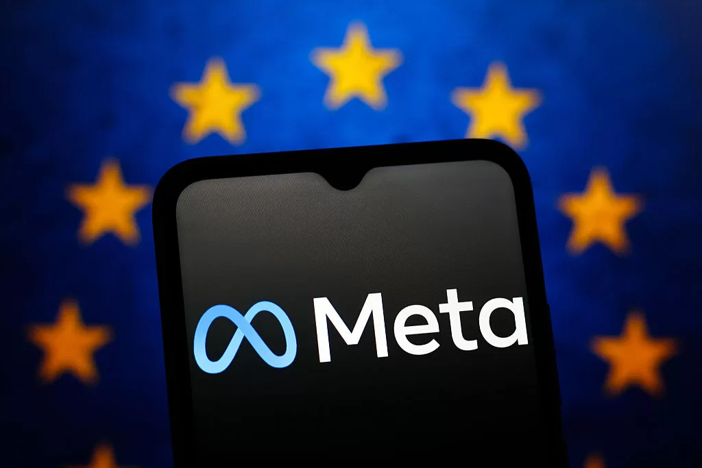 The Meta Platforms logo is seen displayed on a smartphone screen and the flag of the European Union in the background.