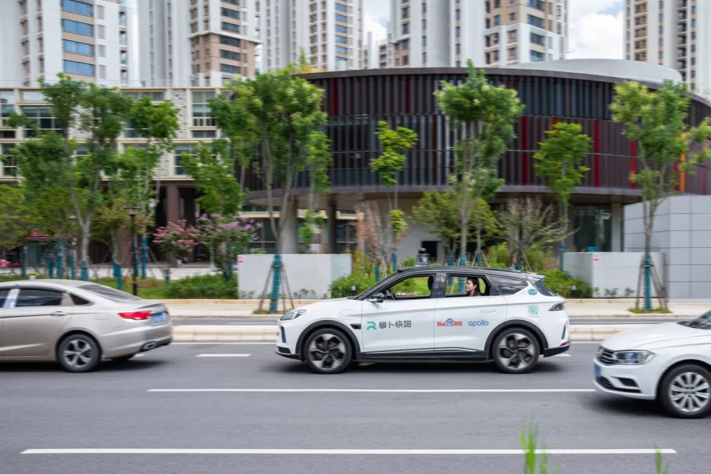 a whilte autonomous vehicle on a city street, with apollo branding