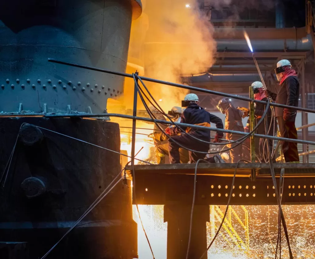 Steel workers releasing molten metal into a mould.