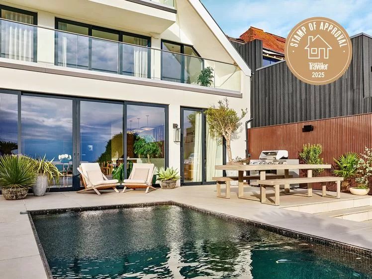 الصورة قد تحتوي على: هندسة معمارية، مبنى، منزل، سكن، فيلا، نبات، كرسي، أثاث، مقعد، باب، مسبح، ماء، ومصباح