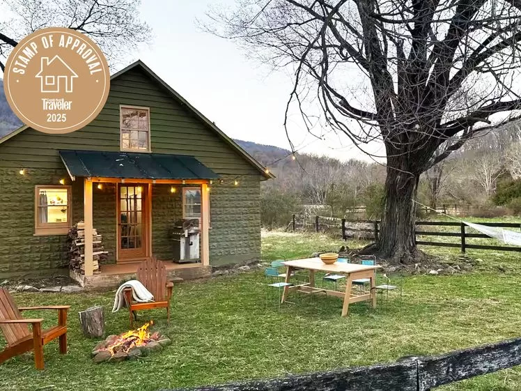 الصورة قد تحتوي على: هندسة، بناء، كوخ، منزل، سكن، كرسي، أثاث، مكتب، طاولة، كوخ، عشب، ونبات