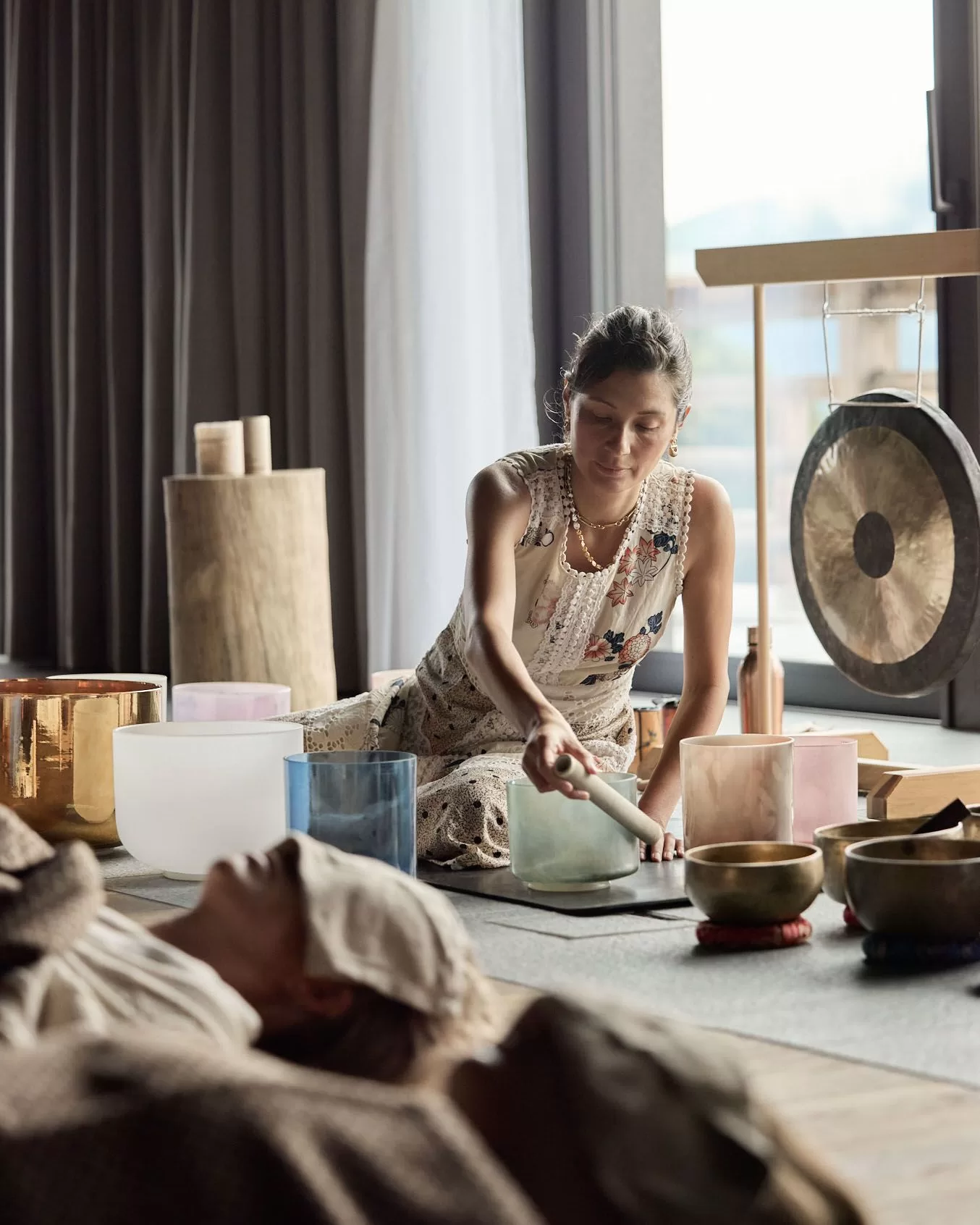 شخص يجلس بجانب جرس في استوديو تمارين أثناء تشغيل أوعية الصوت