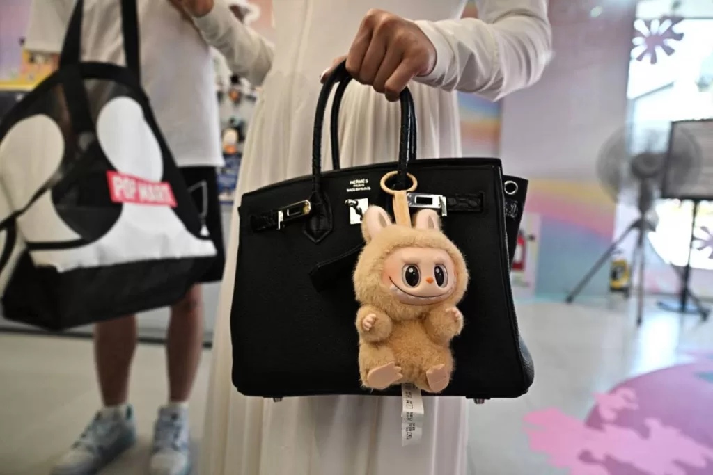 designer art toy Labubu attached to a shopper's handbag at the Pop Mart store in Siam Square in Bangkok. (