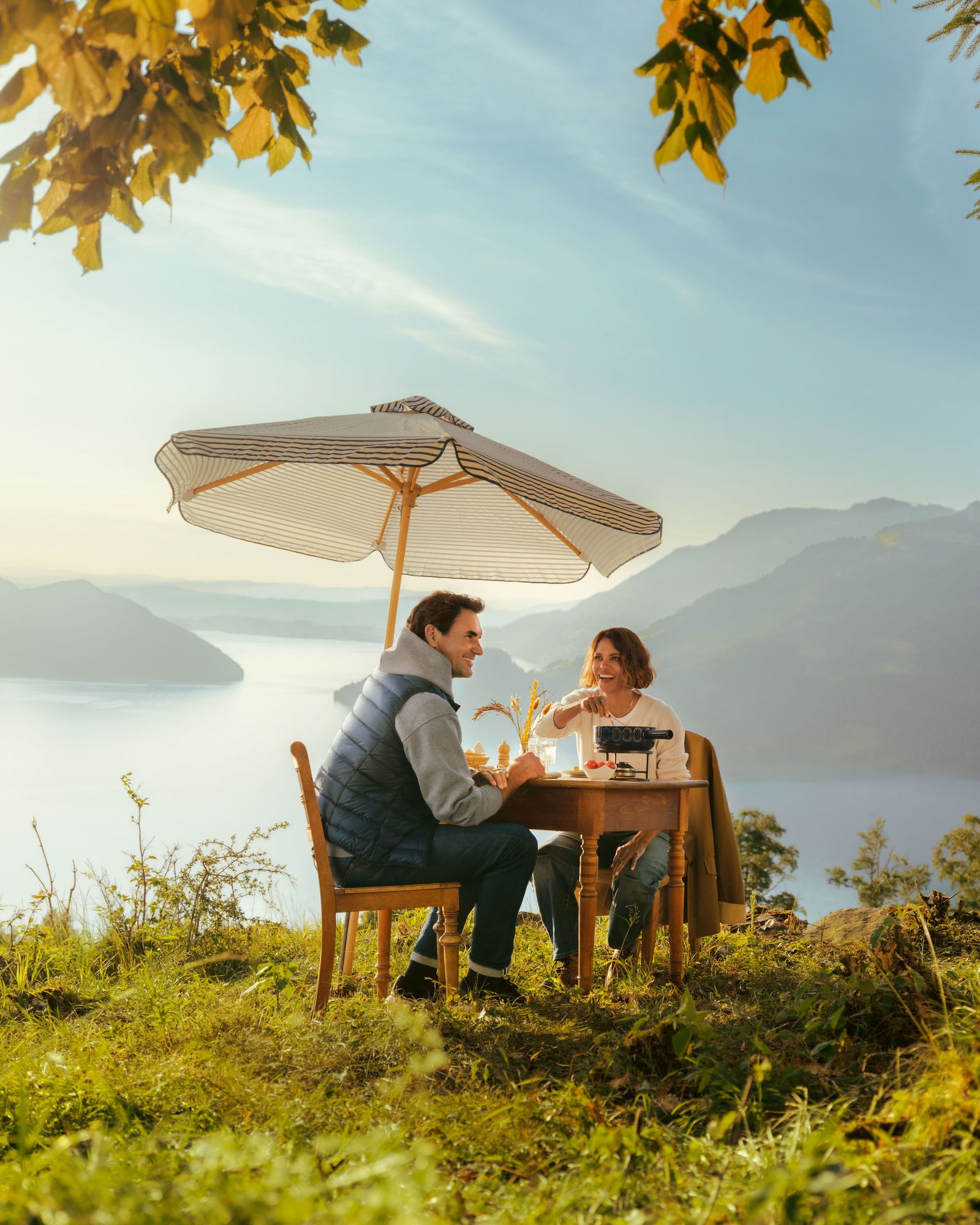 هالي بيري وروجر فيدرير يتناولون الفوندو على طاولة تناول الطعام التي تم إعدادها في الخارج مع إطلالة جميلة على بحيرة لوزيرن في...