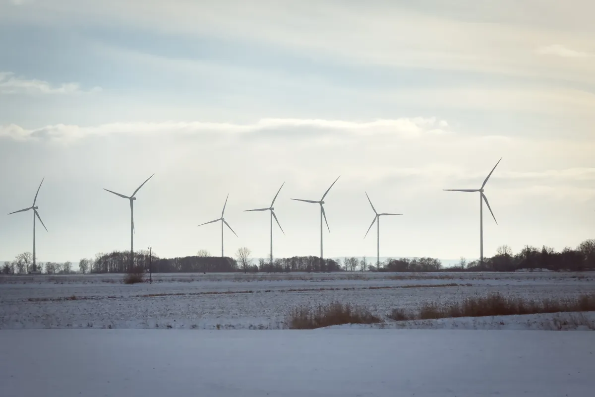 Wind turbines stand across open fields near a railway line in northern Poland, on January 10, 2026.