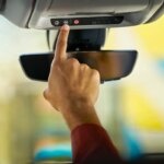 Person pushes the blue OnStar button in a GM vehicle.
