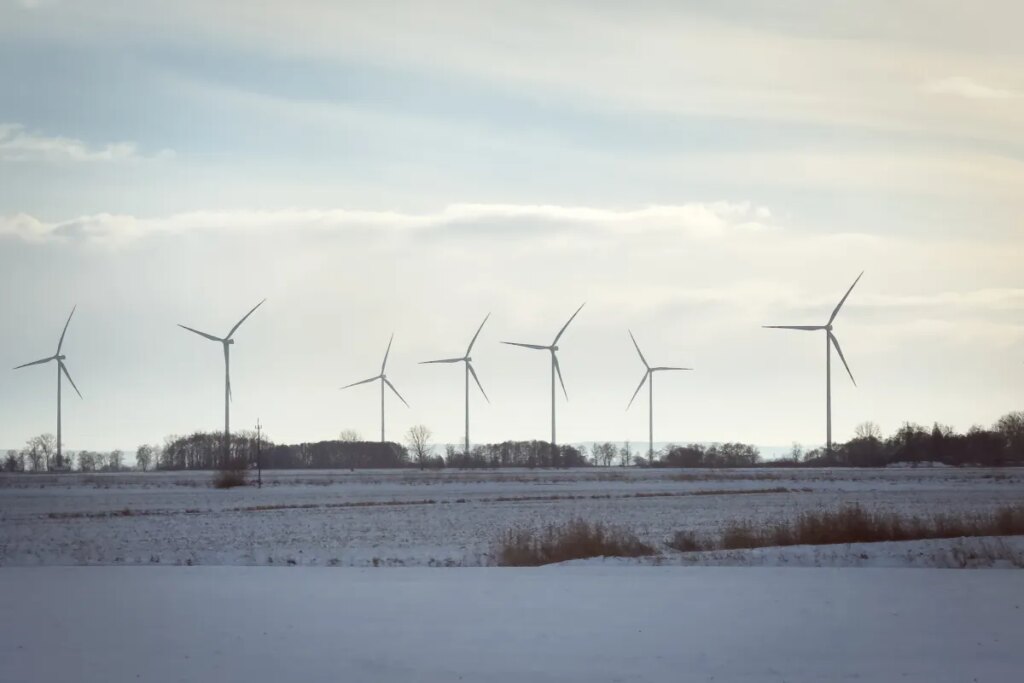 Wind turbines stand across open fields near a railway line in northern Poland, on January 10, 2026.