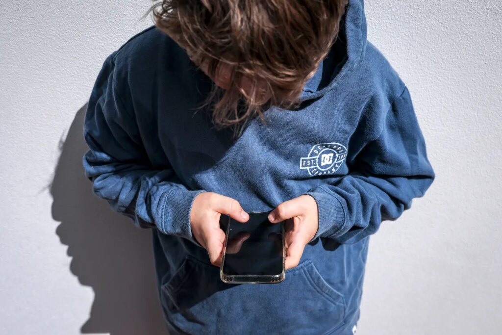 Shows a 14-year-old boy as he looks at social media on his mobile phone.