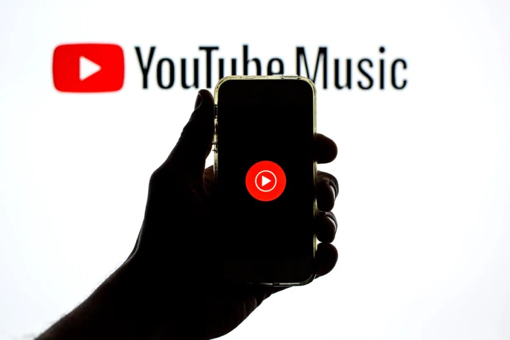 The YouTube Music app seen displayed on a smartphone screen and a YouTube Music logo in the background.