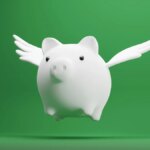 white piggy bank with wings on green background