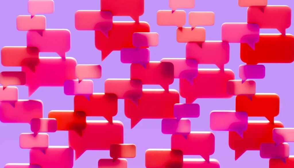 Conceptual image of a dense cluster of three-dimensional speech bubbles in shades of pink red and magenta overlapping and filling the visual field against a solid vibrant purple background.